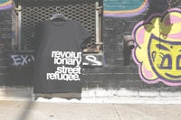 a black t - shirt that says revoltionary street refugee